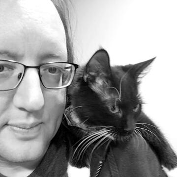Tarver with a tuxedo cat on his shoulder